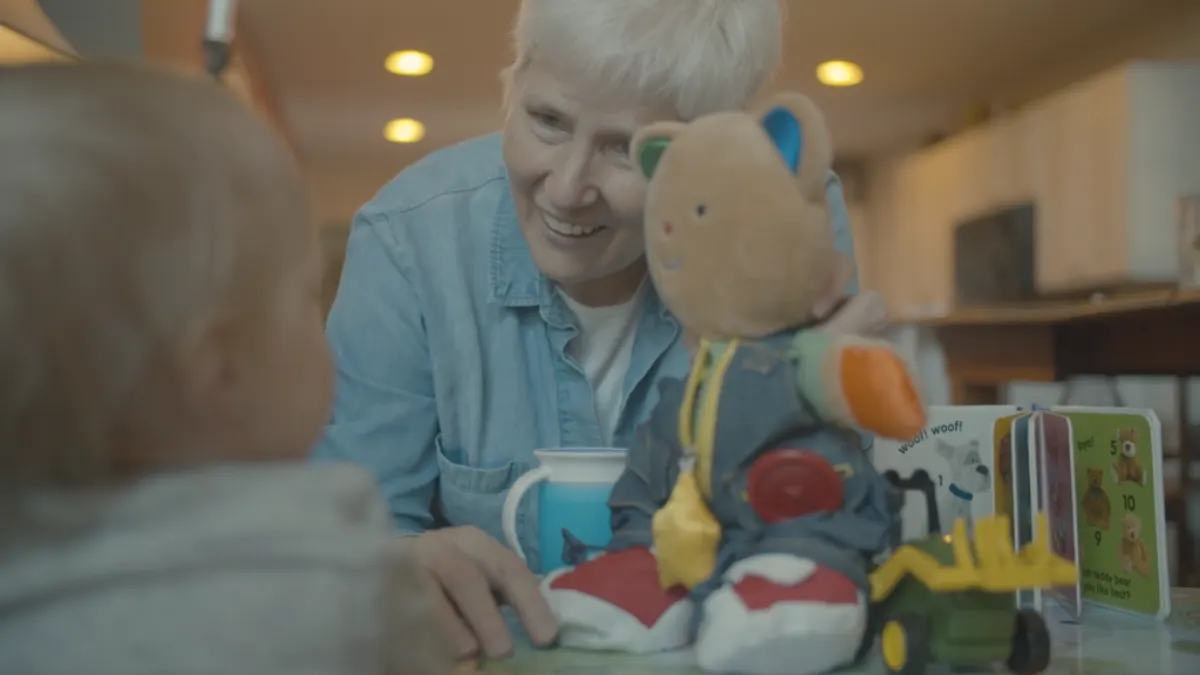 A volunteer family friend smiling with a child and a stuffed animal.