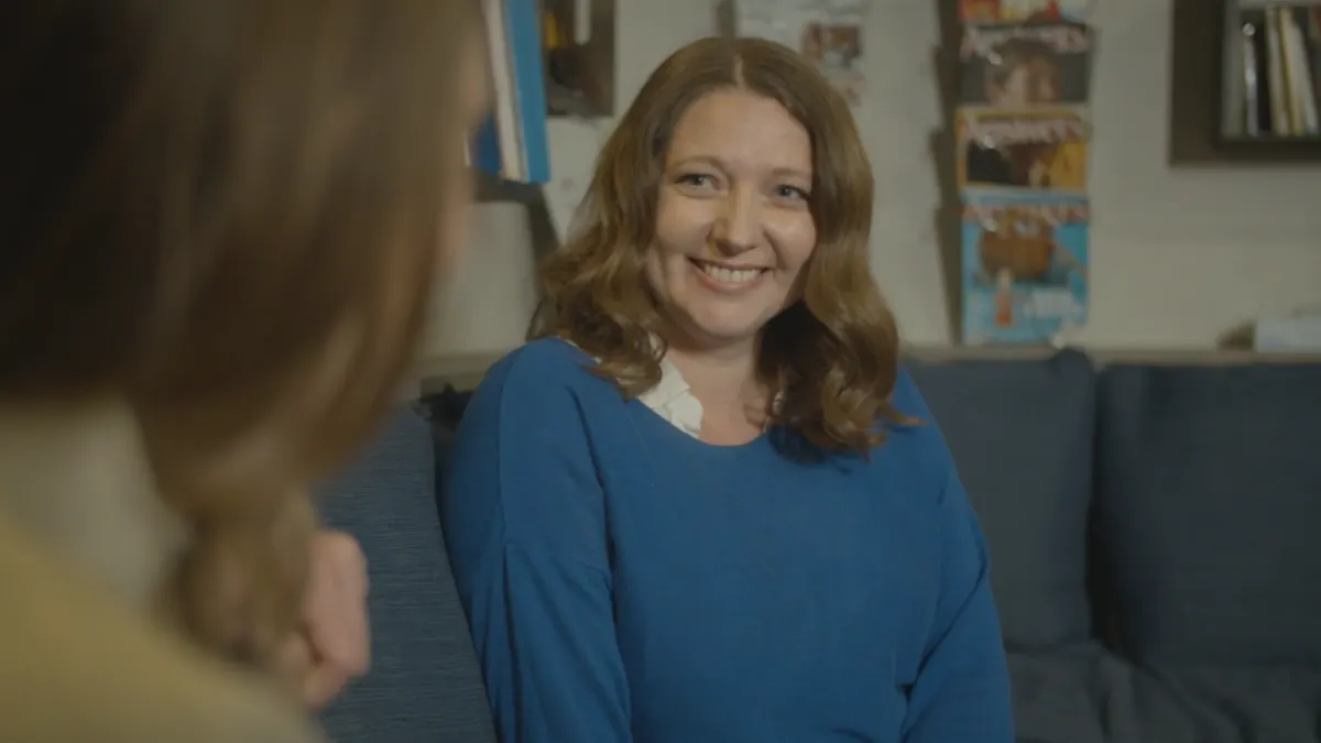 A family coach smiling while talking with a parent.